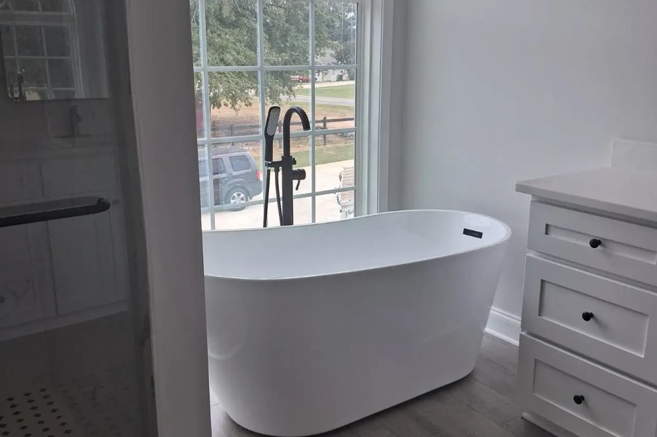 Finished bathroom with a freestanding tub by an arched window